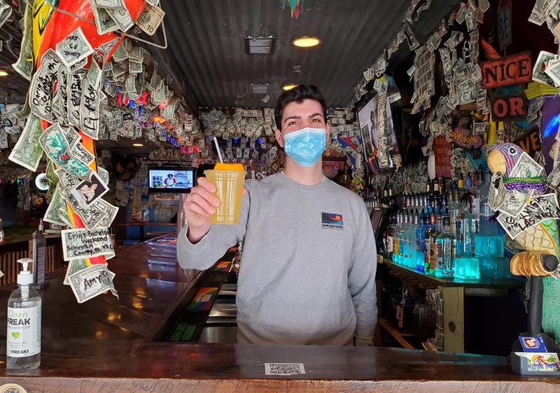 Sam West, a manager at the Purple Parrot in Rehoboth Beach, shows off a to-go orange crush. The state has passed a law formally extending outdoor dining and to-go alcohol sales for the state’s restaurants through March 2022. CHRIS FLOOD PHOTOS